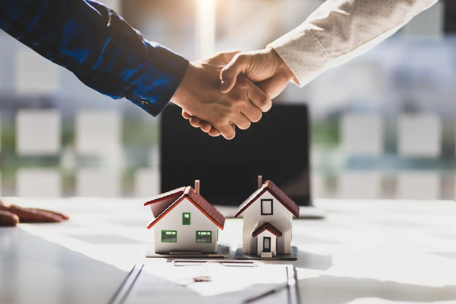 Immobilienmakler schütteln sich nach der Unterzeichnung der Vertragsvereinbarung die Hände.